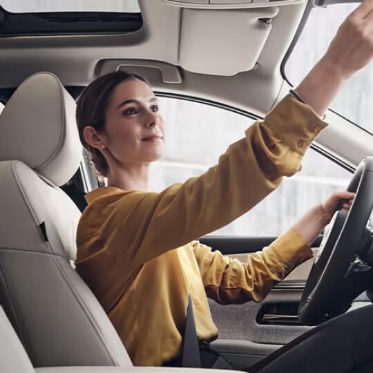 Woman adjusting car mirror