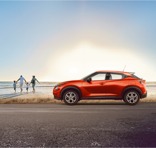 Nissan Juke parked at a roadside beach with family in background