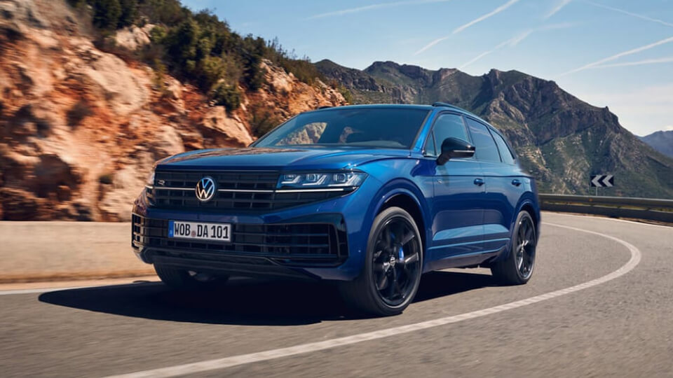 Blue Volkswagen SUV driving on mountain road